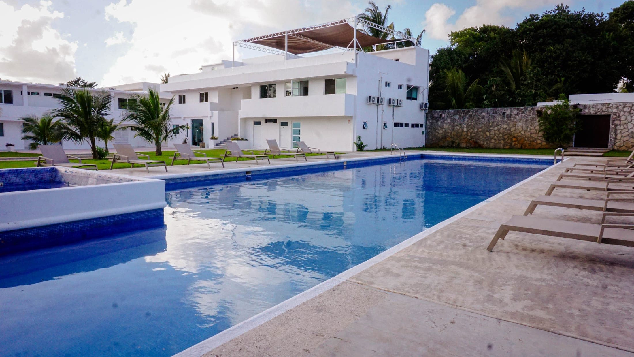 Pool and hotel facade among green areas